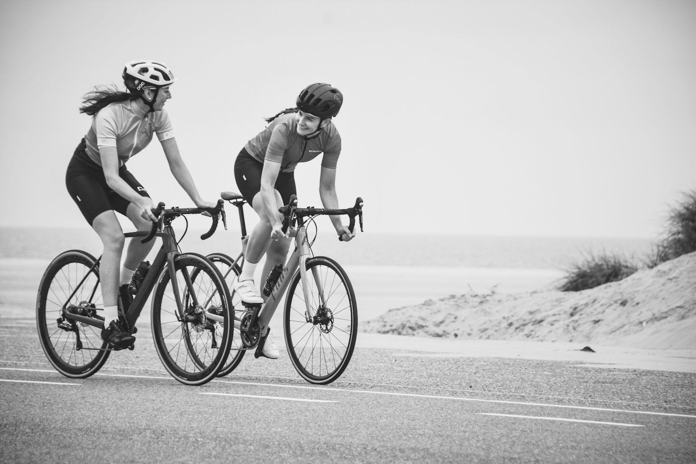 Two riders on road bikes on a coastal road