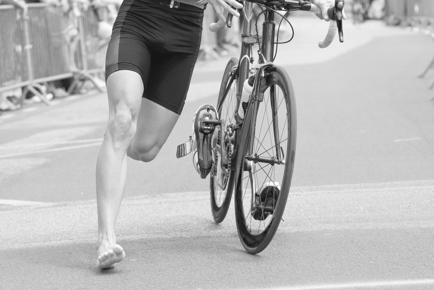 A triathlete running with their bike through transition